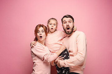 Image showing Surprised young family looking at camera on pink