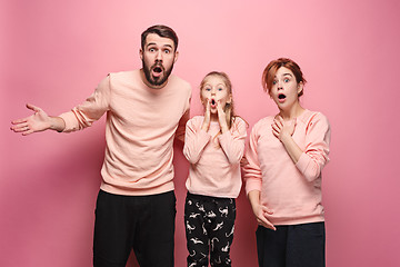 Image showing Surprised young family looking at camera on pink