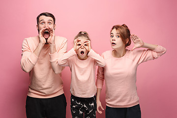 Image showing Surprised young family looking at camera on pink