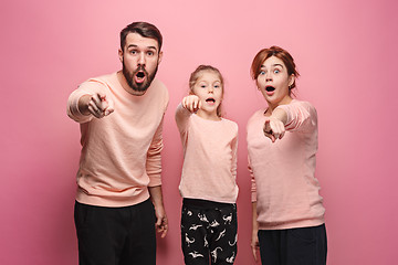 Image showing Surprised young family looking at camera on pink