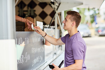 Image showing happy young man paying money at food truck