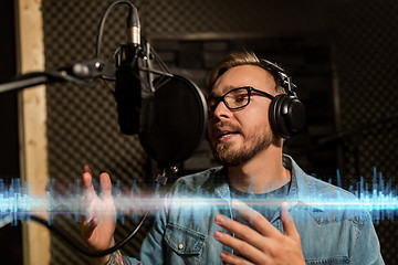 Image showing man with headphones singing at recording studio