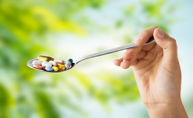 Image showing close up of female hand holding spoon with pills