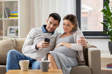 Image showing man and pregnant wife with smartphone at home