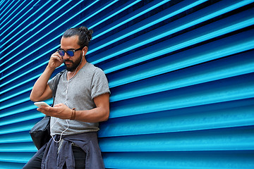 Image showing man with earphones and smartphone over wall