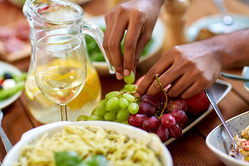 Image showing hands taking grape from plate with fruits