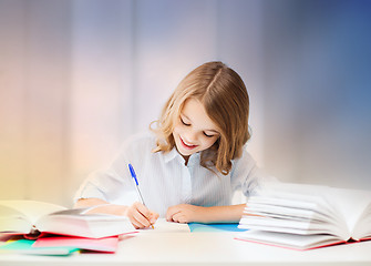 Image showing student girl with books writing in notebook