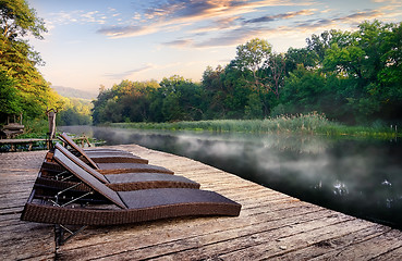 Image showing Chaise longues near river