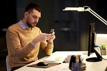 Image showing man with smartphone working late at night office