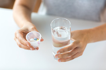 Image showing close up of hands with pills and glass of water