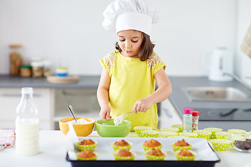 Image showing little girl in chefs toque baking muffins at home