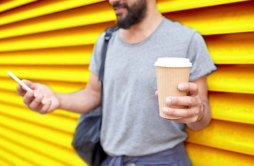 Image showing man with coffee cup and smartphone over wall