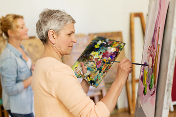 Image showing senior woman painting at art school studio