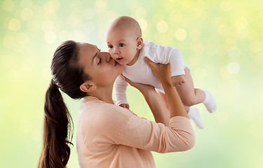 Image showing happy mother kissing little baby boy over green