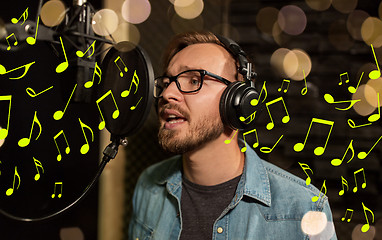 Image showing man with headphones singing at recording studio