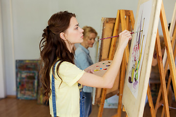 Image showing woman with easel painting at art school studio