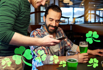 Image showing friends with smartphone drinking green beer at pub