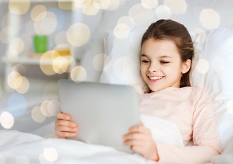 Image showing happy girl in bed with tablet pc over lights