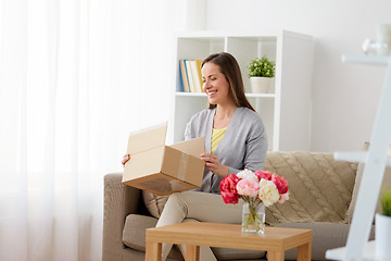 Image showing smiling woman opening parcel box at home