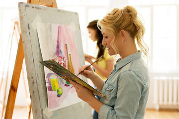 Image showing woman with easel painting at art school studio