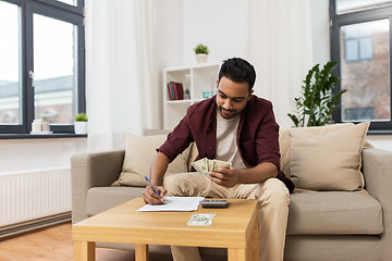 Image showing man with money and calculator filling papers