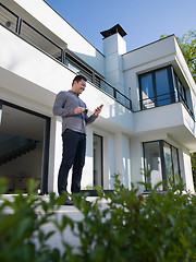 Image showing man using mobile phone in front of his luxury home villa