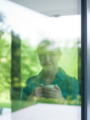 Image showing young woman drinking morning coffee by the window