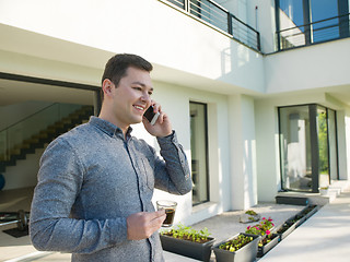 Image showing man using mobile phone in front of his luxury home villa