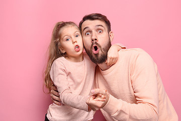 Image showing Surprised young family looking at camera on pink