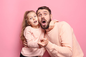Image showing Surprised young family looking at camera on pink