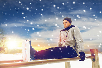 Image showing young man exercising on parallel bars in winter