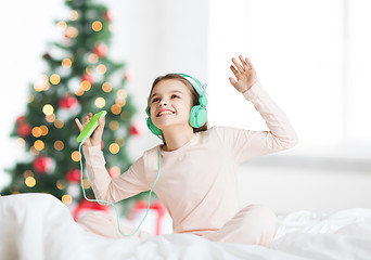 Image showing girl with smartphone and headphones at christmas