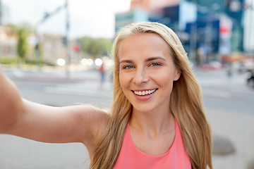 Image showing happy young woman taking selfie on city street