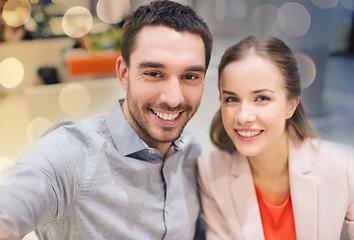 Image showing happy couple taking selfie in mall or office