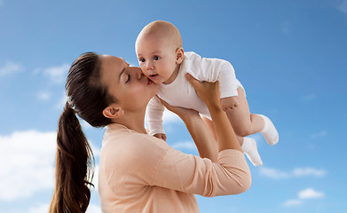 Image showing happy mother kissing little baby boy over sky