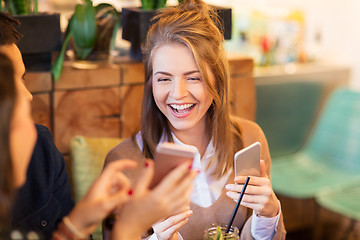 Image showing woman with smartphone and friends at restaurant