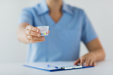 Image showing close up of doctor with pills in medical cup