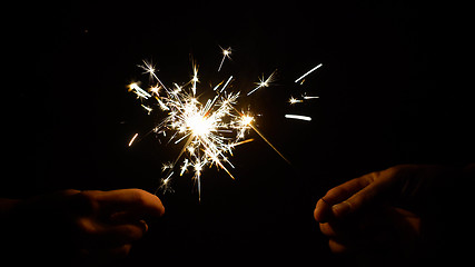 Image showing hands holding burning sparklers or bengal lights