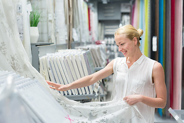 Image showing Beautiful housewife buying white curtains in home decor furnishings store.