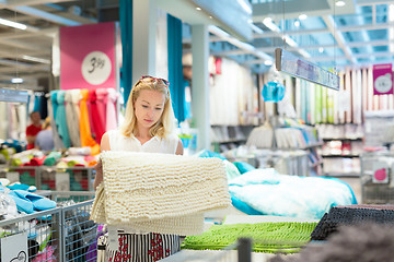 Image showing Woman choosing a mat in modern home furnishings store.