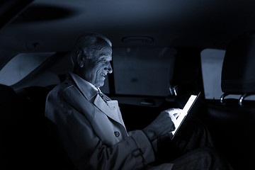 Image showing Businessman with a digital tablet sitting in the back seat of a car