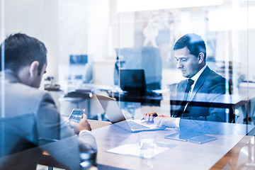 Image showing Two young businessmen using laptop computer at business meeting.