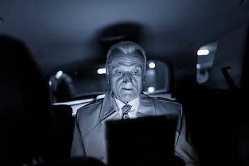 Image showing Businessman with a digital tablet sitting in the back seat of a car
