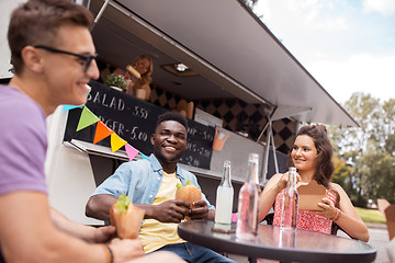 Image showing happy friends with drinks eating at food truck