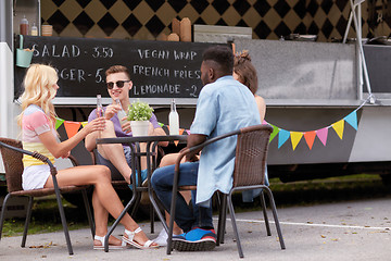 Image showing friends with drinks sitting at table at food truck