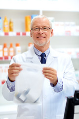 Image showing senior apothecary at pharmacy cash register