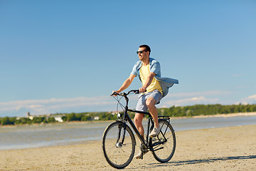 Image showing happy man riding bicycle along summer beach