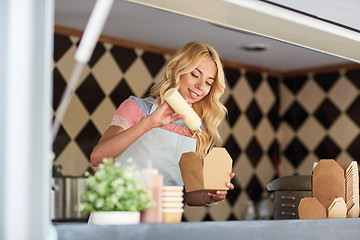 Image showing happy saleswoman making wok at food truck