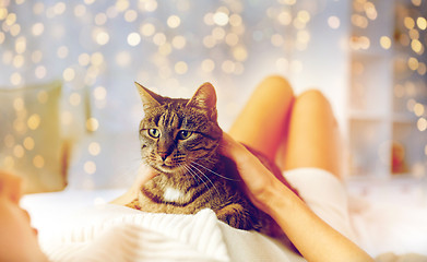 Image showing happy young woman with cat lying in bed at home