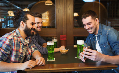 Image showing friends with smartphone drinking green beer at pub